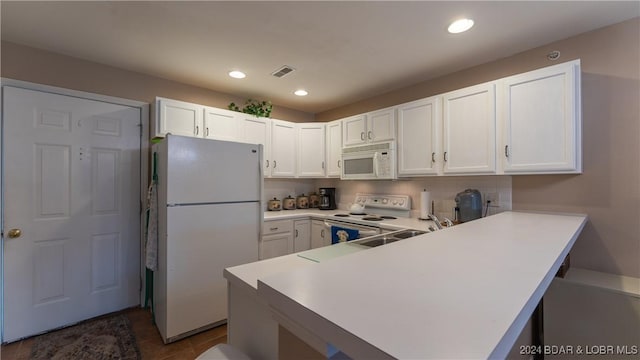 kitchen featuring white appliances, white cabinets, dark tile patterned flooring, sink, and kitchen peninsula