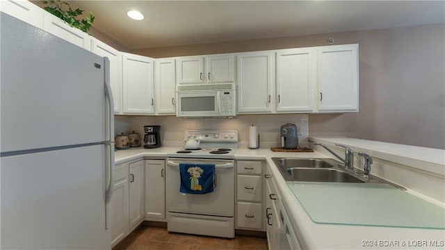 kitchen with white appliances, dark tile patterned flooring, sink, decorative backsplash, and white cabinetry