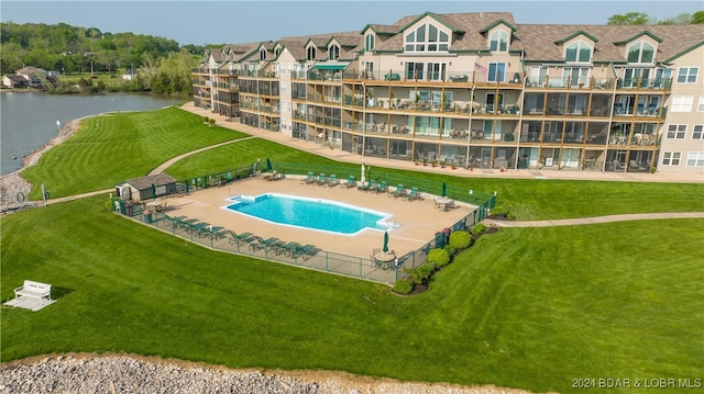 view of pool with a water view and a yard