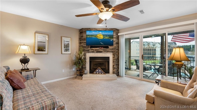 living room with carpet, a stone fireplace, and ceiling fan