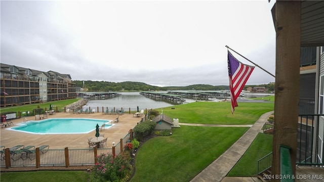 view of swimming pool with a patio, a water view, and a lawn