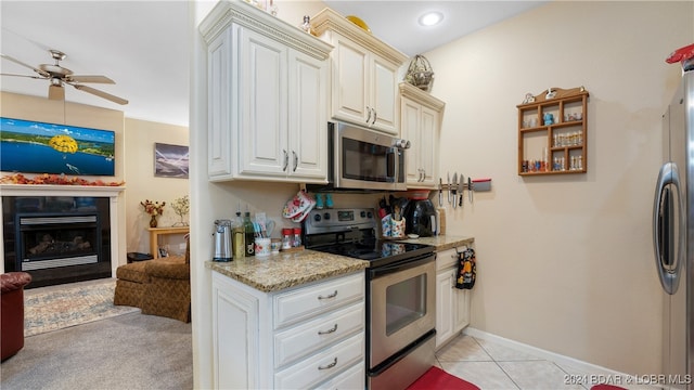 kitchen featuring light tile patterned floors, ceiling fan, stainless steel appliances, and light stone counters