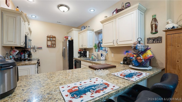 kitchen with light stone countertops, stainless steel appliances, sink, and a kitchen breakfast bar