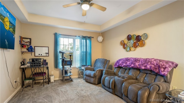 living room with a raised ceiling, carpet flooring, and ceiling fan