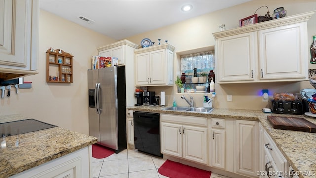 kitchen with light tile patterned flooring, light stone countertops, sink, and black appliances