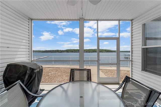 sunroom with a water view and ceiling fan