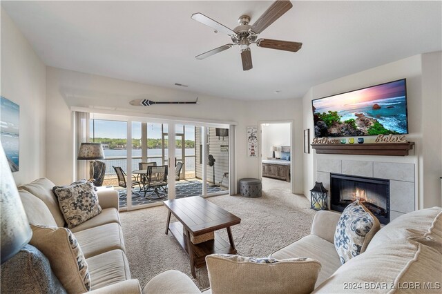 carpeted living room featuring a fireplace and ceiling fan