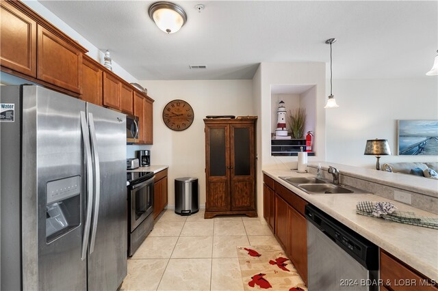 kitchen featuring pendant lighting, appliances with stainless steel finishes, light tile patterned floors, and sink