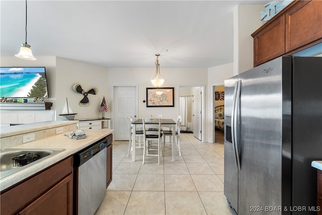 kitchen with stainless steel appliances, light tile patterned flooring, and decorative light fixtures