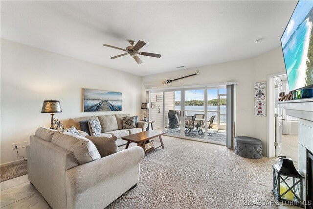 carpeted living room with a tile fireplace and ceiling fan