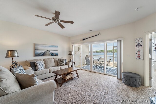 carpeted living room featuring a water view and ceiling fan