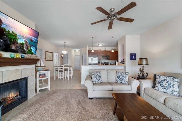 tiled living room featuring ceiling fan and a fireplace