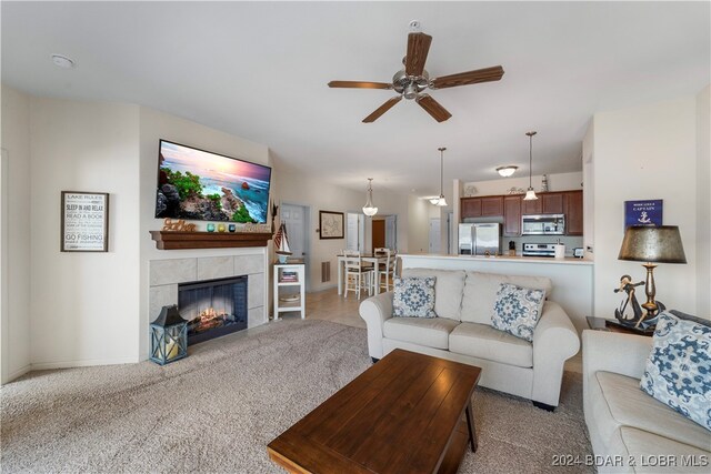 carpeted living room with ceiling fan and a tile fireplace