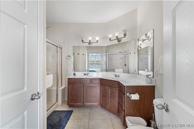 bathroom with tile patterned flooring, a shower with door, and vanity