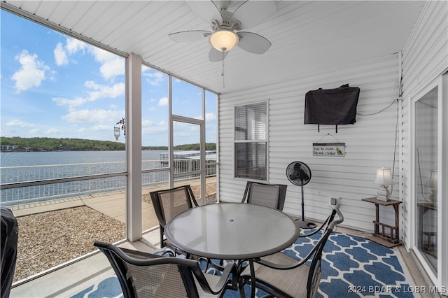 sunroom featuring ceiling fan and a water view