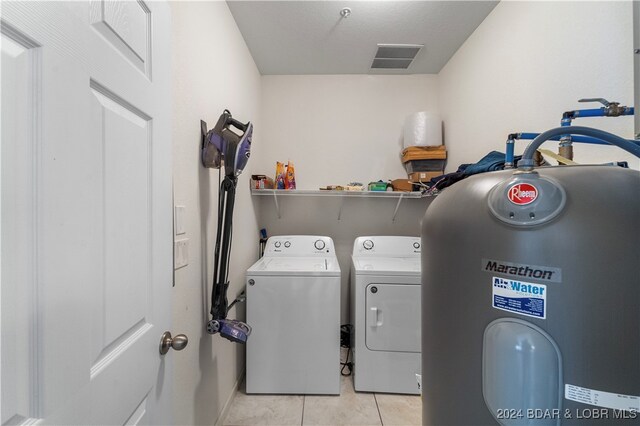 laundry area with water heater, light tile patterned flooring, and washing machine and dryer