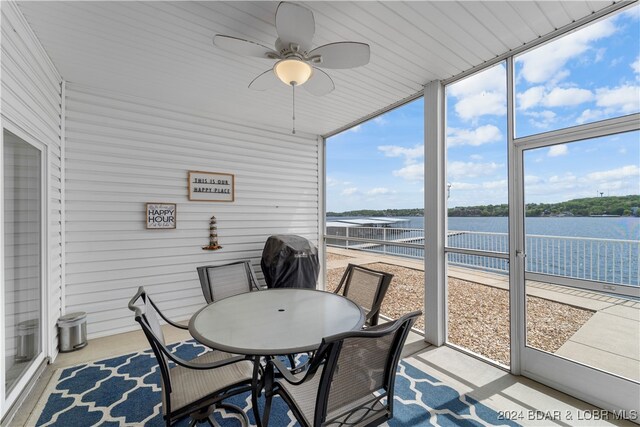 sunroom / solarium with ceiling fan, a water view, and a wealth of natural light