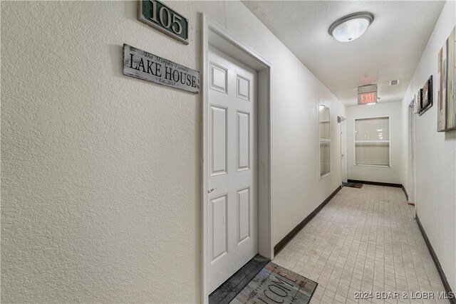 hall featuring a textured ceiling and light tile patterned flooring