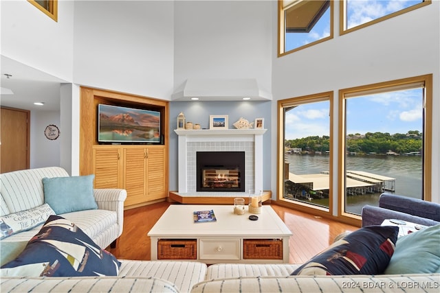 living room with hardwood / wood-style floors, a tile fireplace, and a high ceiling