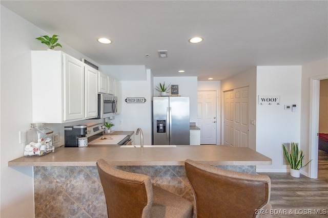 kitchen featuring white cabinets, sink, dark hardwood / wood-style flooring, kitchen peninsula, and stainless steel appliances