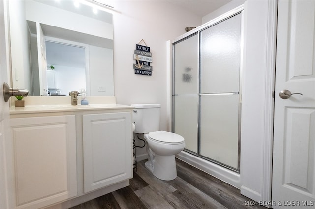 bathroom featuring vanity, hardwood / wood-style flooring, toilet, and a shower with door