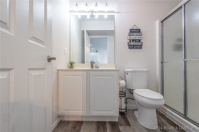 bathroom with hardwood / wood-style flooring, vanity, toilet, and a shower with shower door