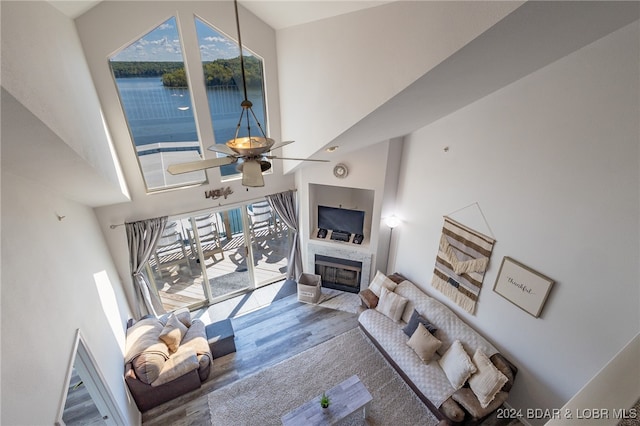 living room with ceiling fan, wood-type flooring, a high ceiling, and a wealth of natural light