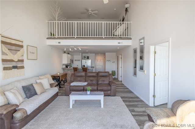 living room with ceiling fan, wood-type flooring, and a high ceiling