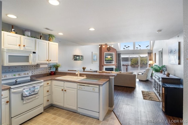 kitchen featuring white appliances, kitchen peninsula, white cabinetry, and sink