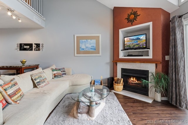 living room featuring a tiled fireplace and dark hardwood / wood-style flooring