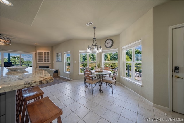 tiled dining room with an inviting chandelier and a healthy amount of sunlight