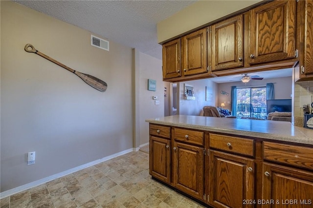 kitchen with ceiling fan, decorative backsplash, a textured ceiling, and kitchen peninsula