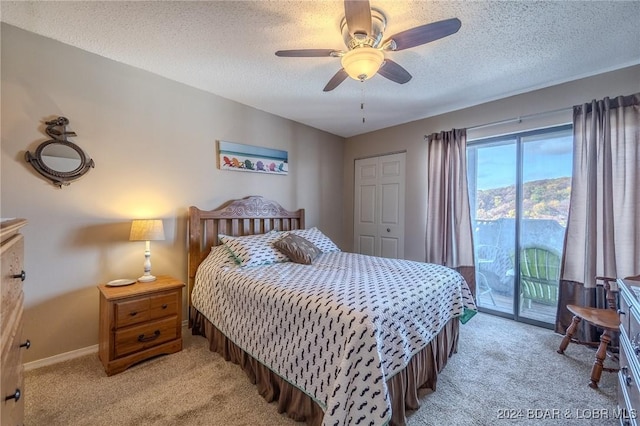 carpeted bedroom with ceiling fan, access to exterior, a textured ceiling, and a closet