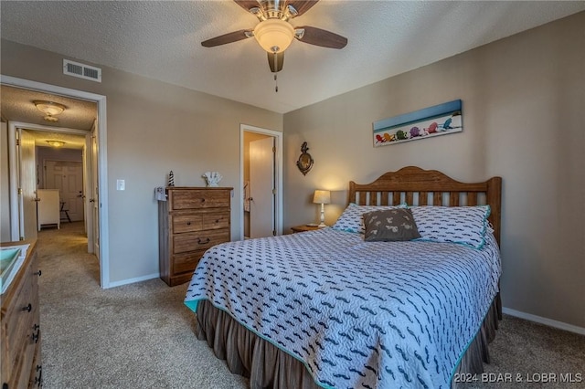 carpeted bedroom featuring ceiling fan and a textured ceiling