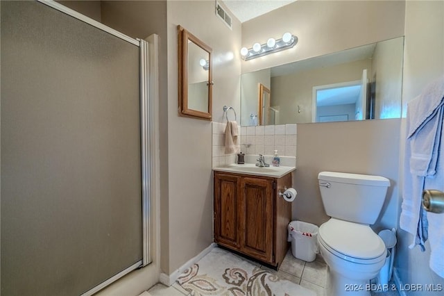 bathroom featuring tile patterned floors, toilet, decorative backsplash, vanity, and a shower with shower door