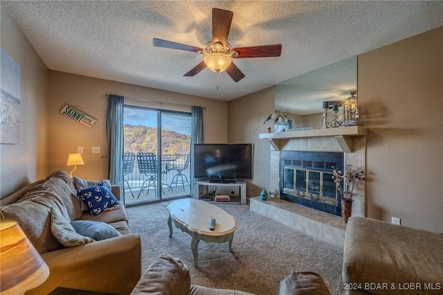 living room featuring ceiling fan, light colored carpet, a textured ceiling, and a tile fireplace