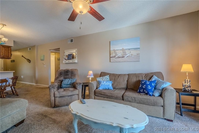 living room featuring a textured ceiling, carpet floors, and ceiling fan