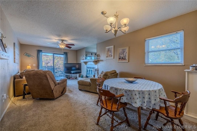 dining area featuring carpet flooring, ceiling fan with notable chandelier, and a textured ceiling