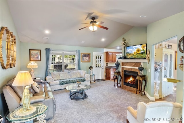 living room featuring a tile fireplace, lofted ceiling, ceiling fan, and light colored carpet