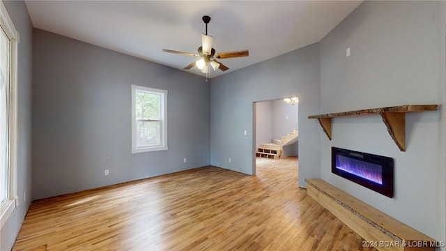 unfurnished living room with ceiling fan, light hardwood / wood-style flooring, and vaulted ceiling