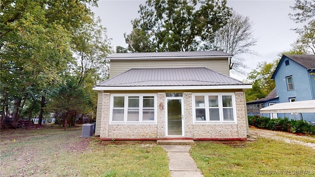 view of front of home with central AC and a front lawn