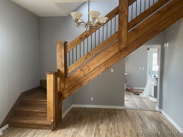 staircase featuring a chandelier and hardwood / wood-style flooring