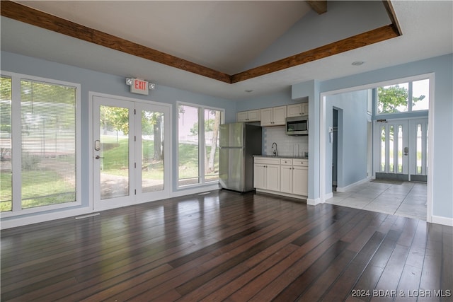 unfurnished living room featuring sink, hardwood / wood-style floors, and vaulted ceiling with beams