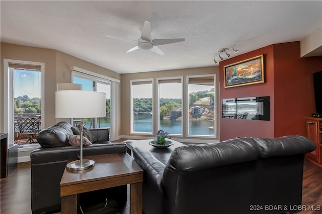 living room with ceiling fan, a textured ceiling, a healthy amount of sunlight, and dark hardwood / wood-style flooring