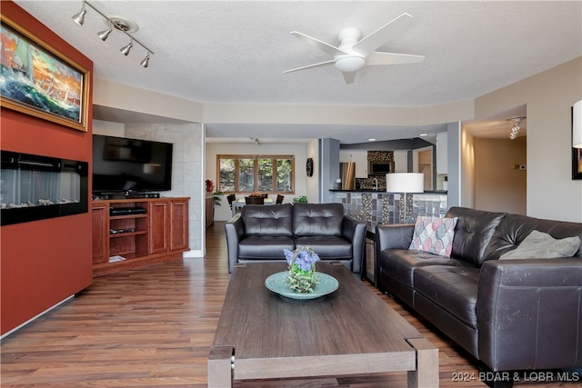 living room with a textured ceiling, hardwood / wood-style flooring, and ceiling fan