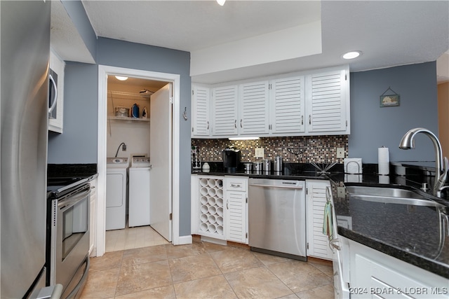 kitchen featuring decorative backsplash, sink, white cabinetry, appliances with stainless steel finishes, and washing machine and dryer