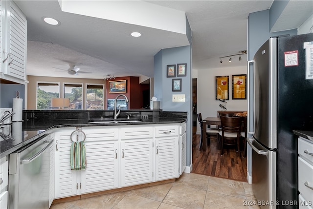 kitchen featuring appliances with stainless steel finishes, light tile patterned flooring, sink, white cabinetry, and dark stone counters