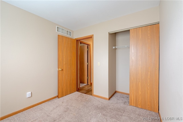 unfurnished bedroom featuring light carpet and a closet