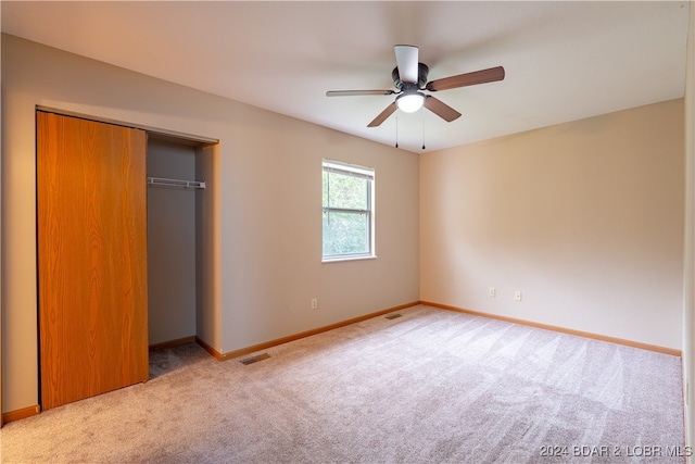 unfurnished bedroom featuring ceiling fan, light colored carpet, and a closet