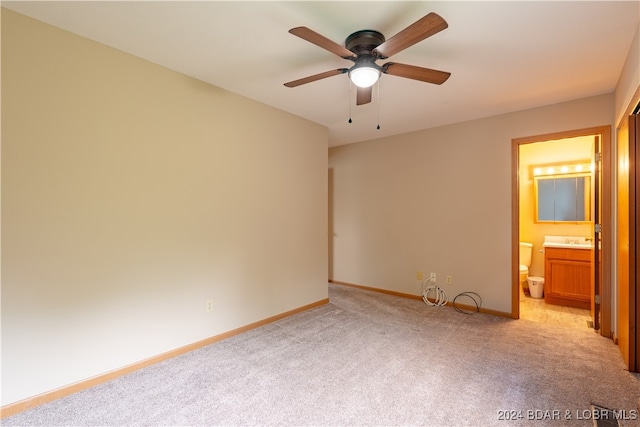 unfurnished bedroom with ensuite bathroom, ceiling fan, sink, and light carpet